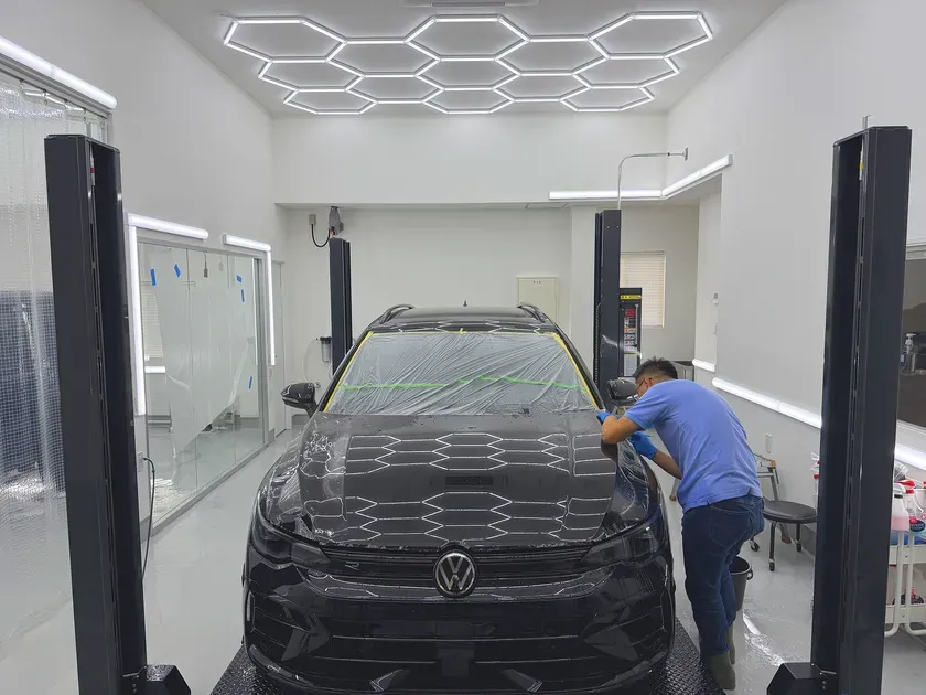 洗車場で黒い車を丁寧に洗車している男性の様子