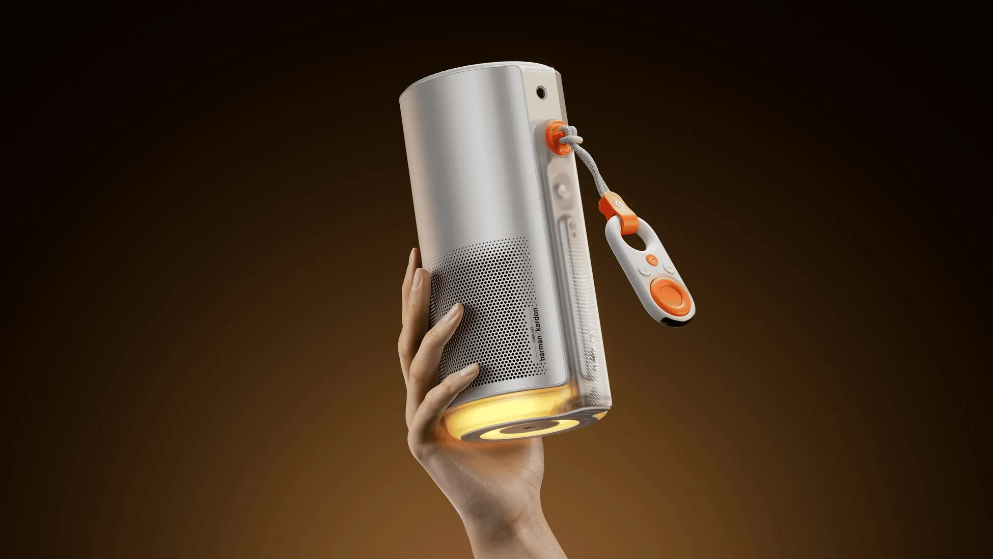 女性の手が白い円筒形のデバイスを持ち、オレンジ色のアクセントが付いたリモコンがぶら下がっている画像です。デバイスの底は黄色く光っています。背景は茶色です。