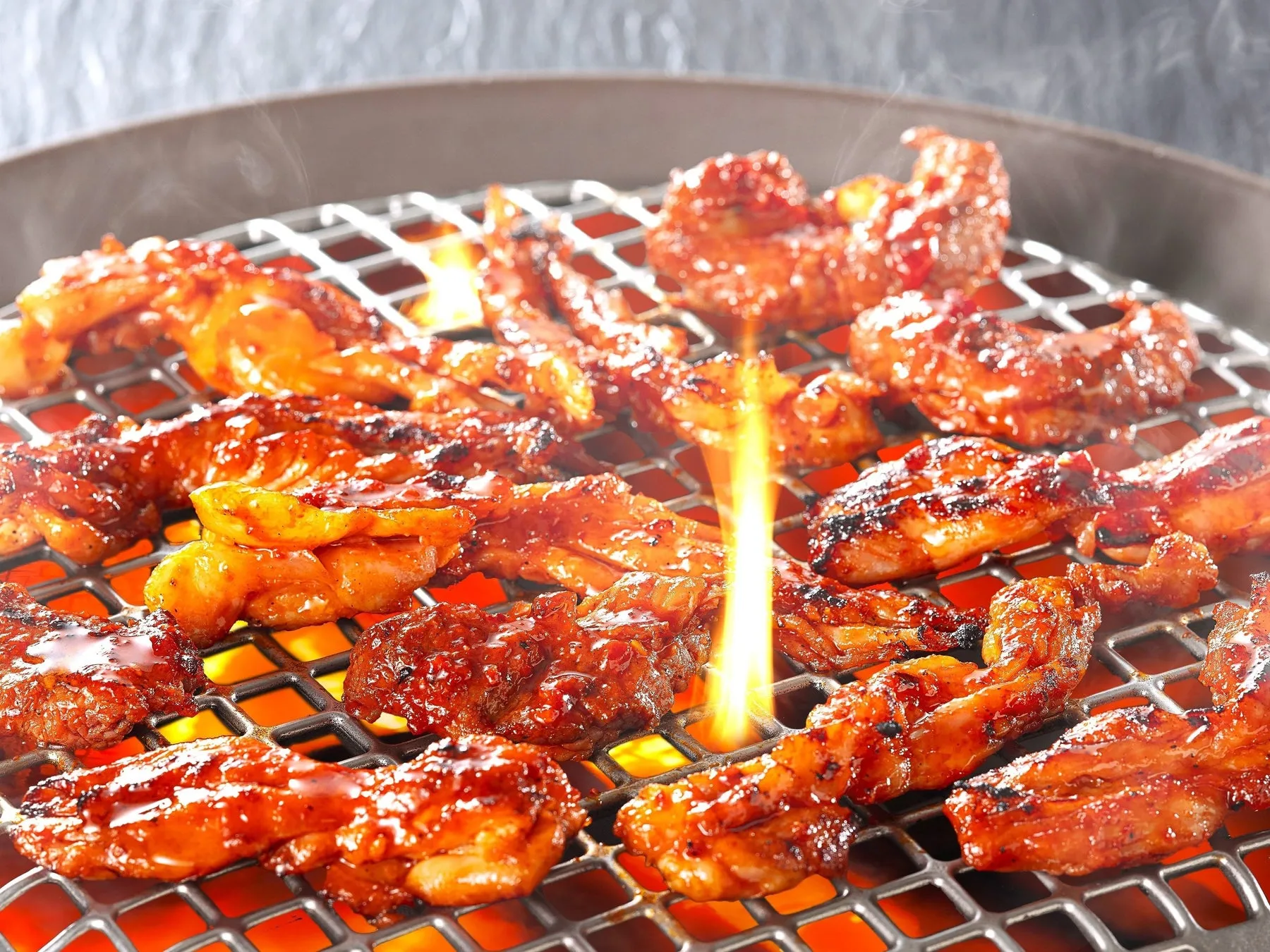 焼かれた鶏肉が網の上で焼かれている様子を捉えた写真。