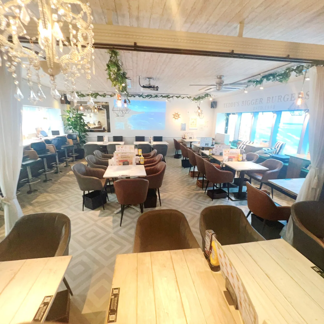 レストランのインテリア。テーブルと椅子が配置され、照明や装飾が施されている。