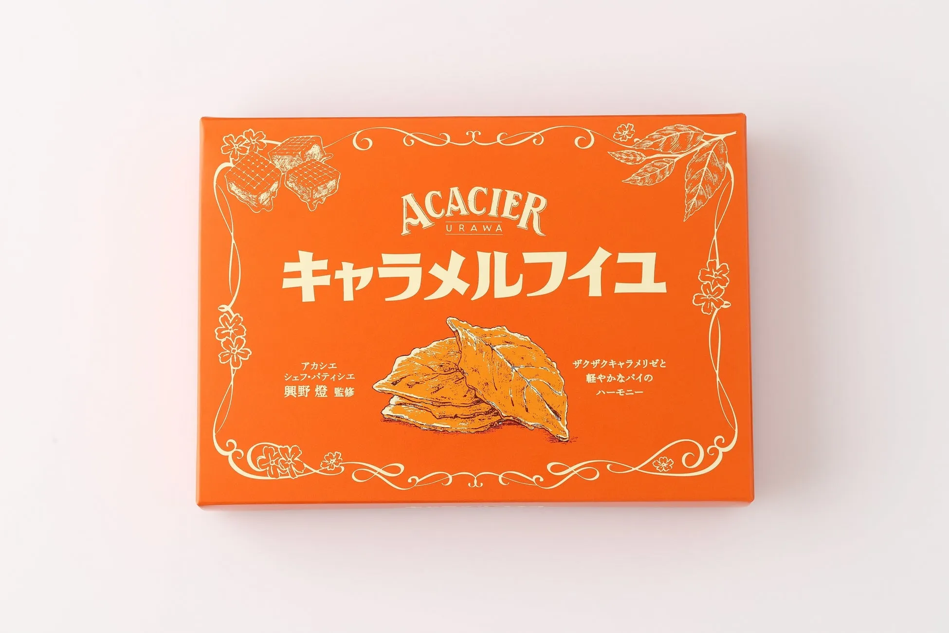 オレンジ色のパッケージに「ACACIER」の文字と「キャラメルフイユ」の文字が書かれた商品の写真です。パッケージには、商品の説明やシェフの名前なども記載されています。