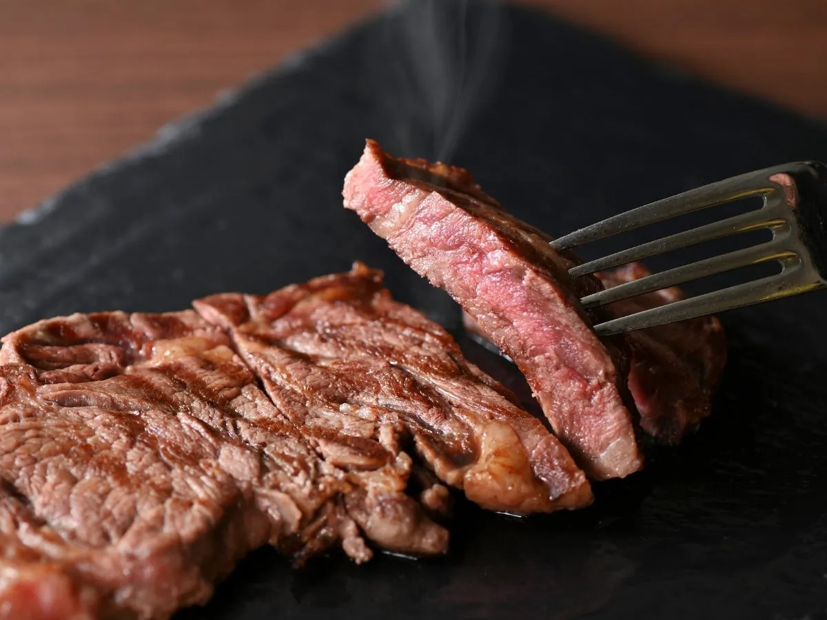 ステーキがフォークで持たれており、切り口が見えている様子。