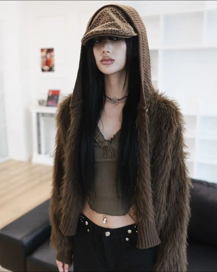 茶色のふわふわしたジャケットとフード付きの帽子をかぶり、おへそにピアスをした女性のクローズアップ。