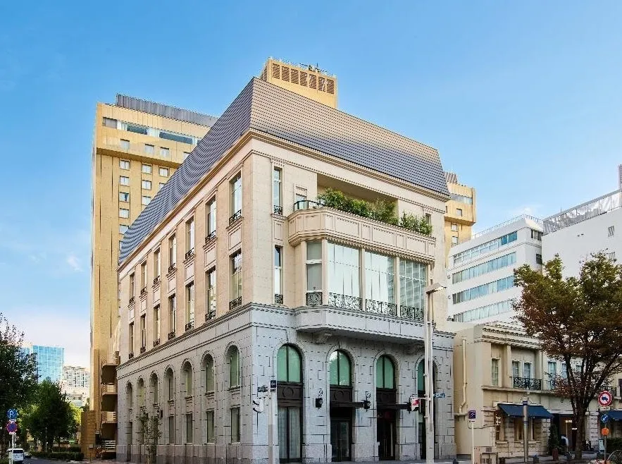 街角にある美しい建物の写真。明るい空の下、洗練されたデザインの建物が際立っています。