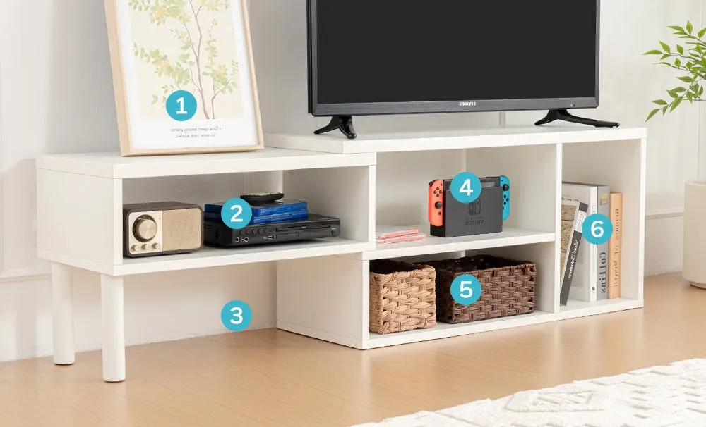 白いテレビ台の上にテレビ、絵、スピーカー、DVDプレーヤー、Nintendo Switch、かご、本が置かれている様子。
