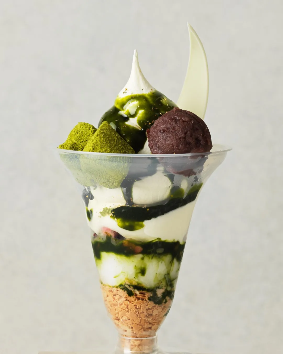 抹茶パフェの写真です。ソフトクリーム、抹茶ソース、白チョコ、あんこ、抹茶パウダー、クッキーなどが入っています。