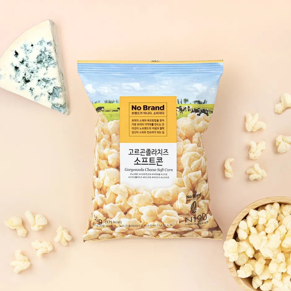 ゴルゴンゾーラチーズソフトコーンのスナック菓子とチーズの画像です。パッケージには「No Brand」のロゴと、製品名、栄養情報が記載されています。周りには、スナック菓子とチーズが配置されています。