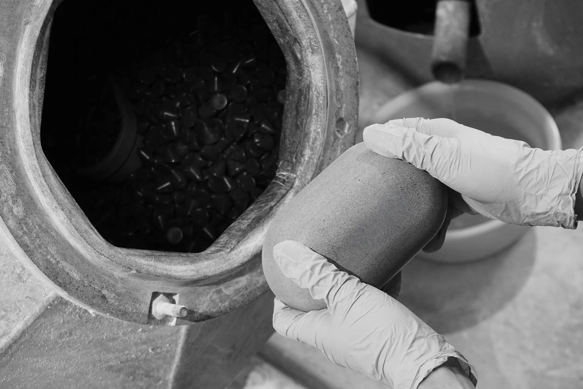 手袋をした手が容器から取り出された物体を持っている白黒写真