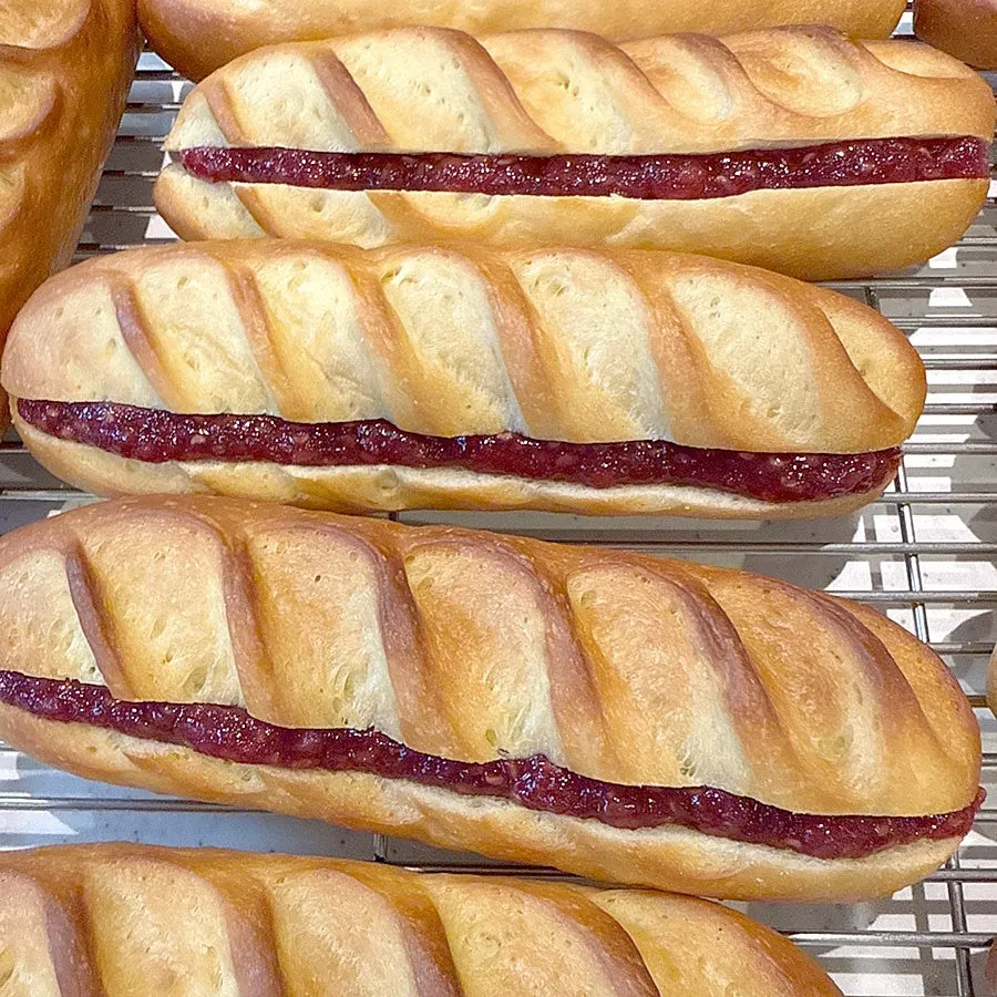 バゲットパンに赤いジャムが挟まれた写真