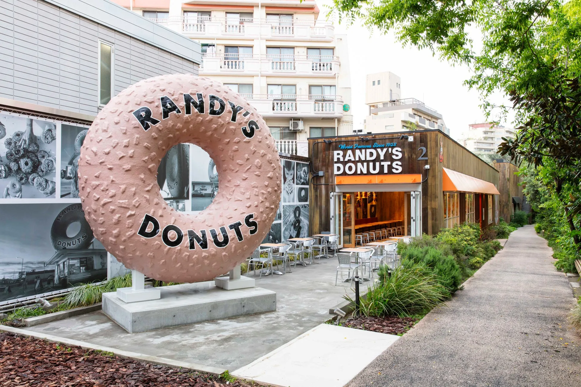 巨大なドーナツのオブジェが特徴的なお店「Randy's Donuts」の外観。店の入り口にはテーブルと椅子が並び、テイクアウトもできるようです。