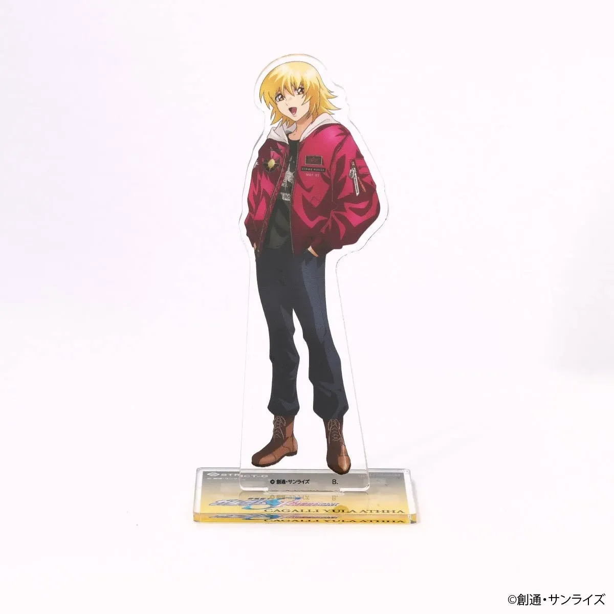 アクリルスタンドのキャラクターは、金髪で赤いジャケットと黒いパンツを着た女性です。スタンドには「CAGALLI YULA ATHHA」の文字が刻まれています。