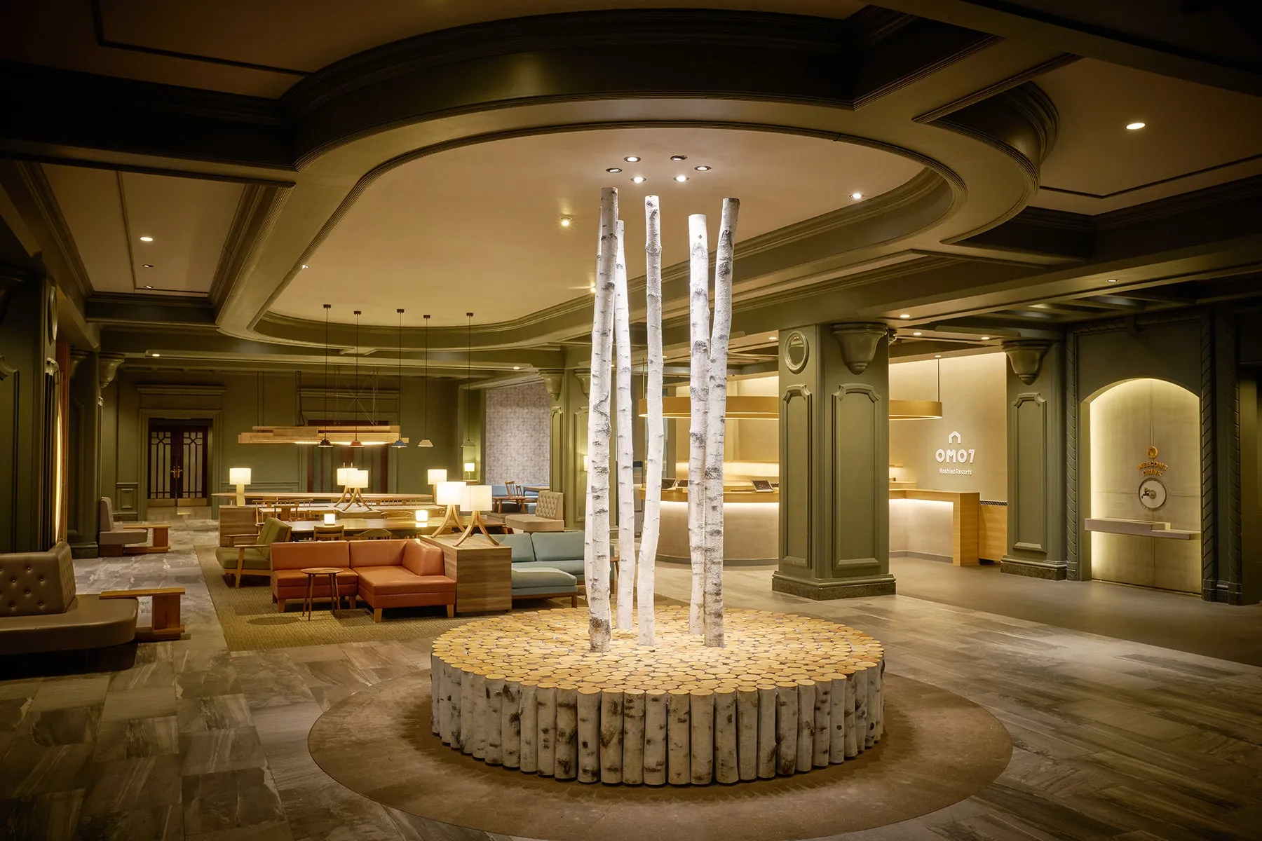 ホテルのロビーの写真。ロビーの中央には切り株で作られた円形の台があり、その上に白い幹の木が立っている。奥には受付があり、OMO7のロゴが見える。