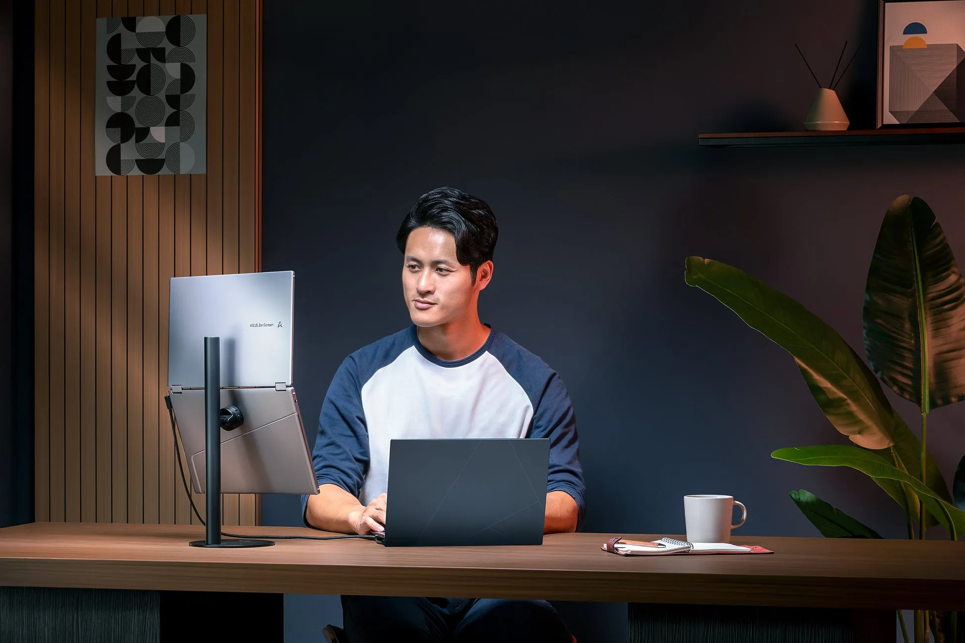 男性がノートパソコンとデュアルモニターを使用してデスクで作業している様子