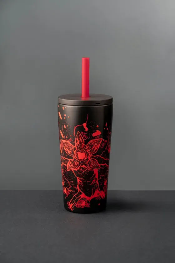 黒いタンブラーで、赤いストローが付いています。タンブラーには、赤い色でデモゴルゴンが描かれています。