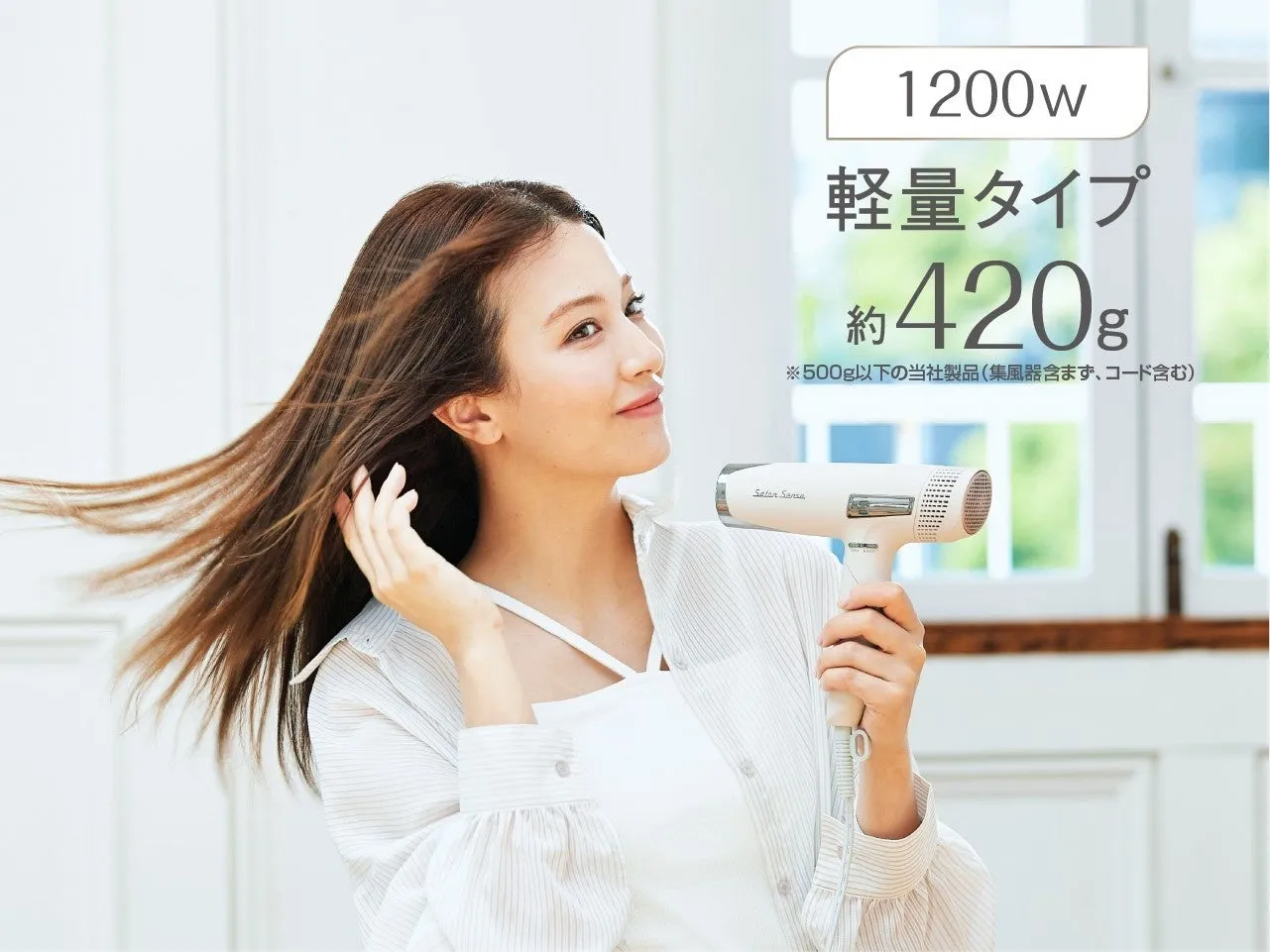 女性がヘアドライヤーを持って髪を乾かしている様子。ヘアドライヤーは白く、軽量タイプで1200wであることが示されている。