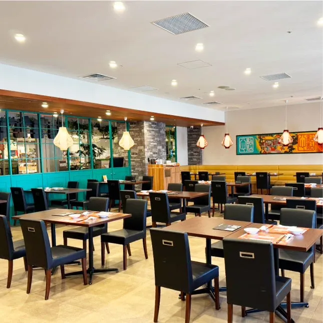 レストランのインテリア。テーブルと椅子が並んでおり、照明が吊り下げられている。