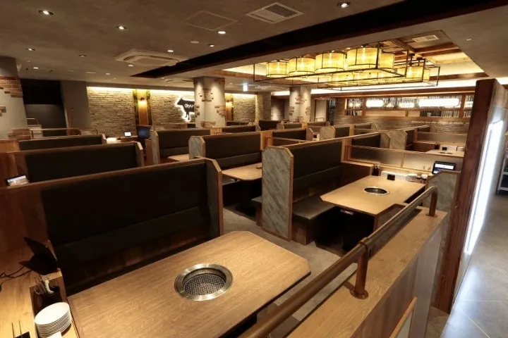 焼肉店の内観写真です。テーブル席が並び、照明が特徴的です。