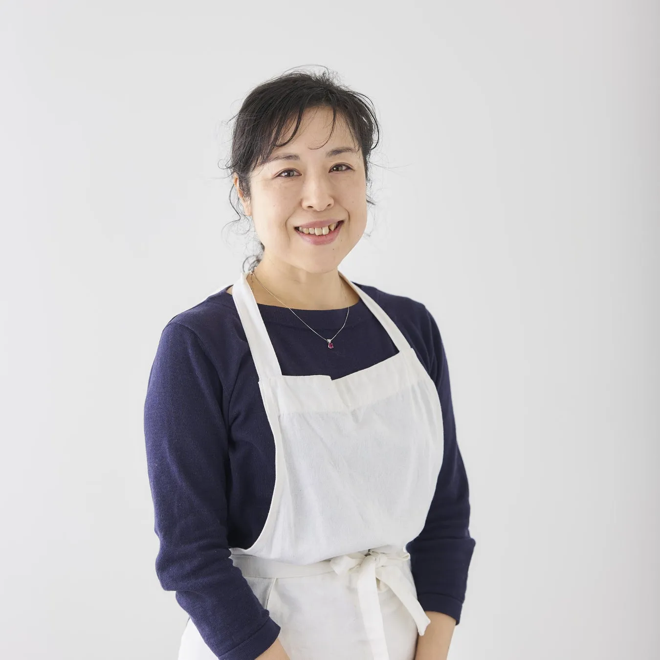 白いエプロンを着た女性が微笑んでいるポートレート