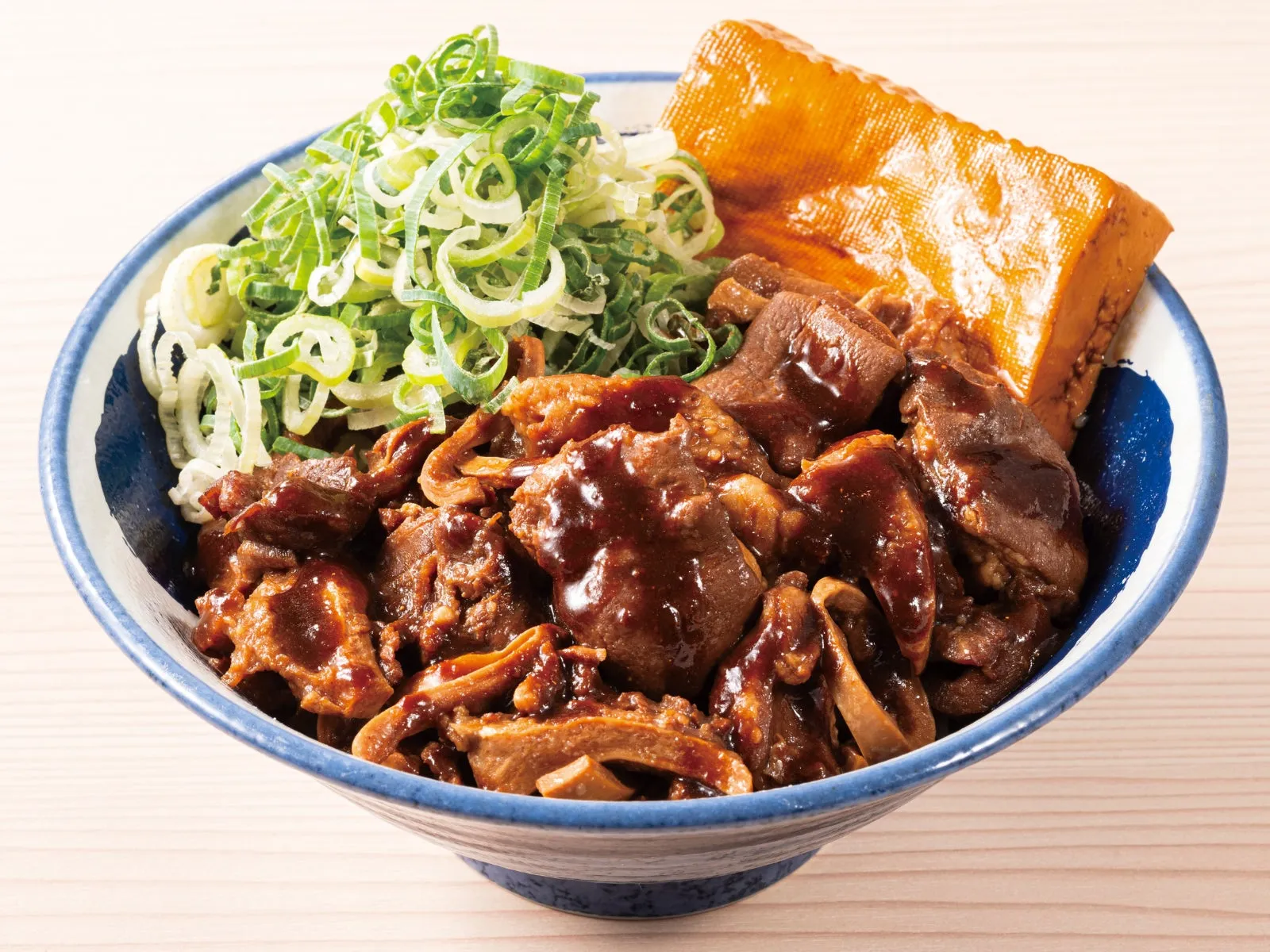 丼に入った料理。具材は煮込まれた肉、ネギ、揚げ豆腐のように見えるもの。