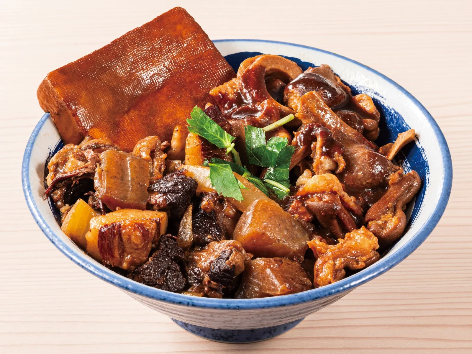 丼に入った角煮のような料理。大きな揚げ豆腐のようなものも乗っている。