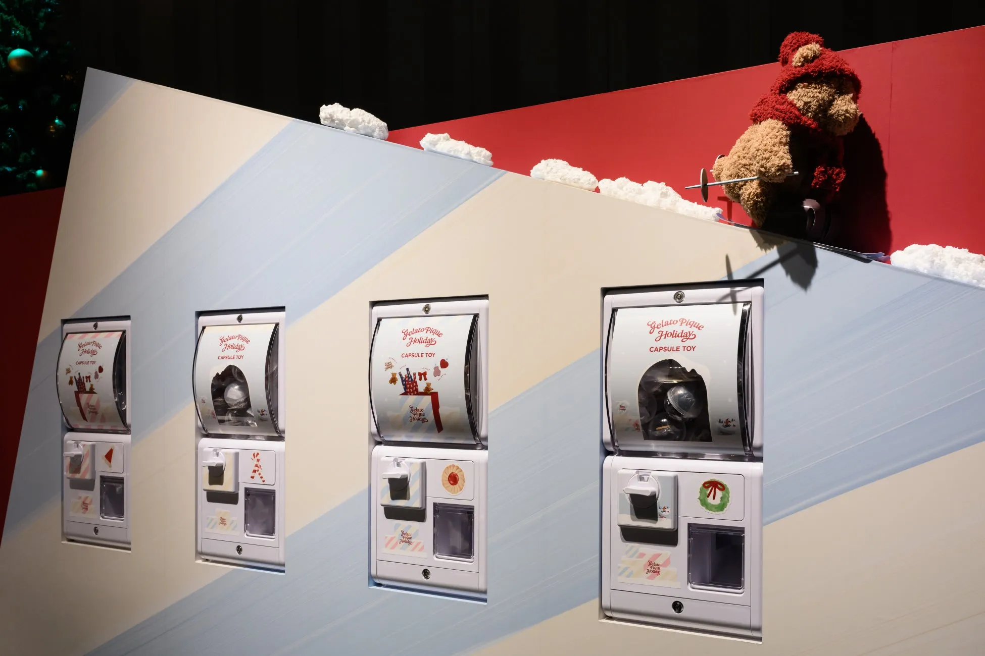 ガチャガチャが並んだ写真。ガチャガチャの上には雪を模した装飾があり、クマのぬいぐるみも飾られている。それぞれのガチャガチャには、Gelato Pique Holidayの文字が見える。