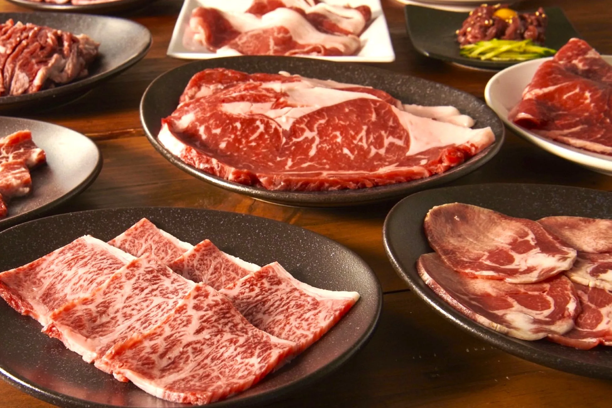 様々な種類の焼肉が皿に盛り付けられた写真です。霜降り肉、タン、ハラミ、ユッケなど、様々な部位が並んでいます。