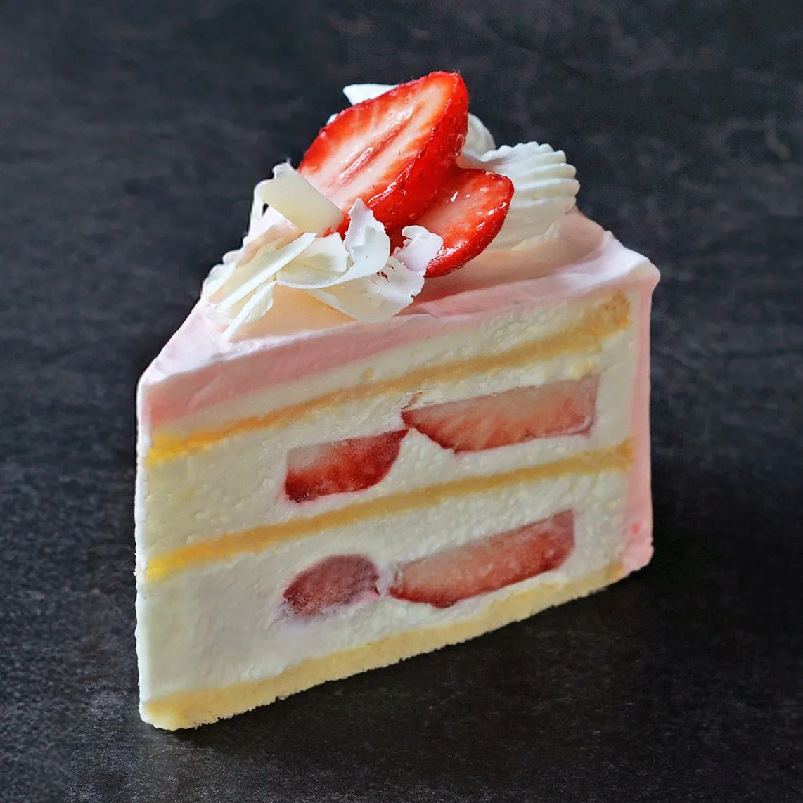 いちごがトッピングされたケーキの断面図。スポンジ生地とクリーム、いちごが層になっている。