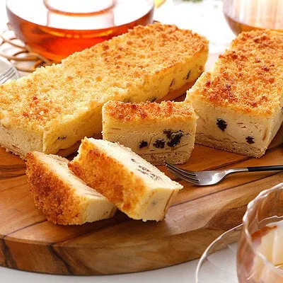 木製のまな板の上に、クッキーのようなものが乗っている写真です。いくつかカットされており、フォークも添えられています。飲み物やティーポットも写っています。