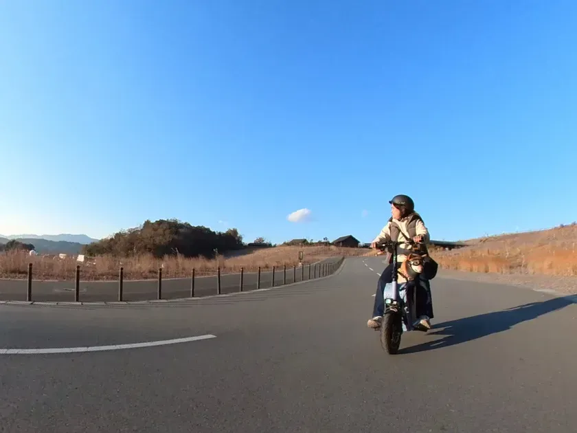 電動スクーターに乗って道路を走る人