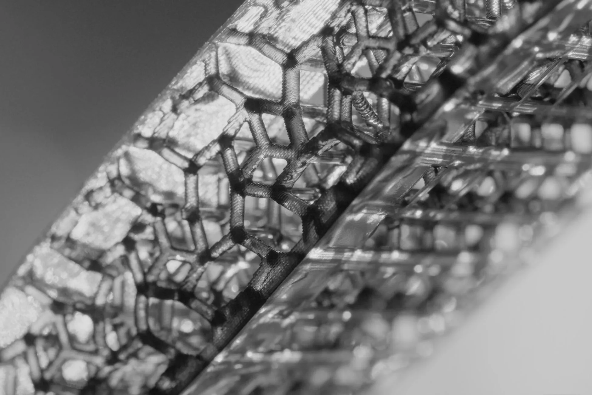 六角形の構造を持つ、幾何学的な模様のクローズアップ写真。光沢のある表面と影が、奥行きと質感を与えています。