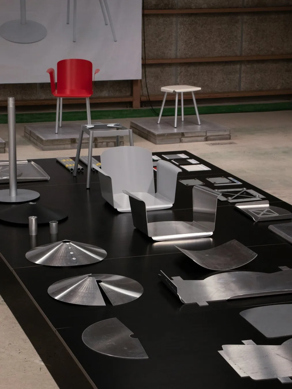 赤、白、グレーの椅子や金属製の部品が並べられた写真。