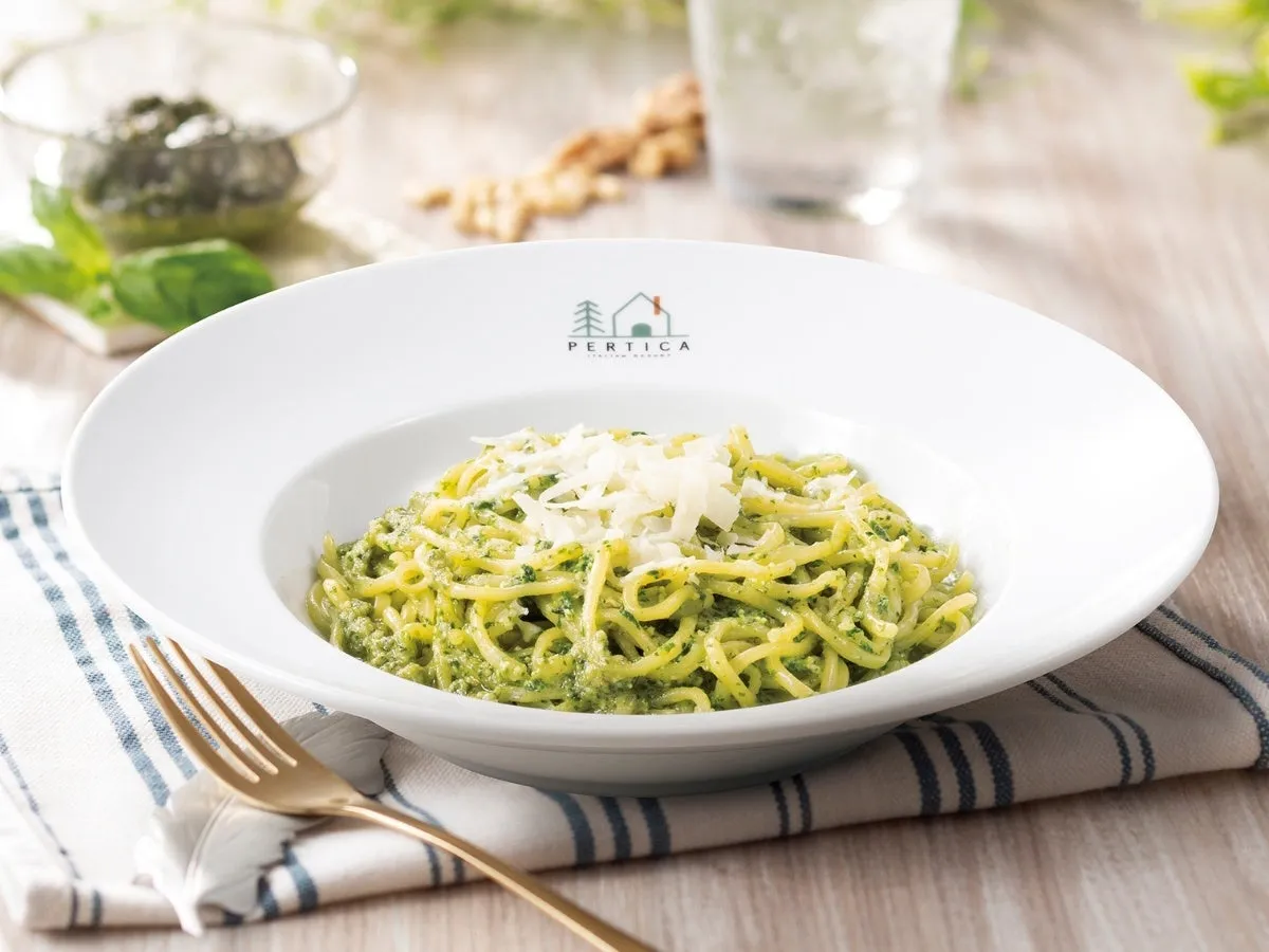 パスタ料理の写真。白い皿に盛られたジェノベーゼパスタがメインで、チーズがトッピングされている。