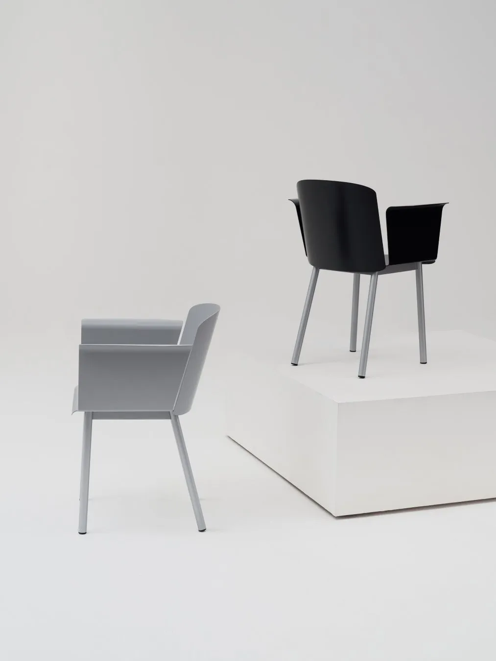 白い背景に置かれた2つの椅子の画像。グレーと黒。