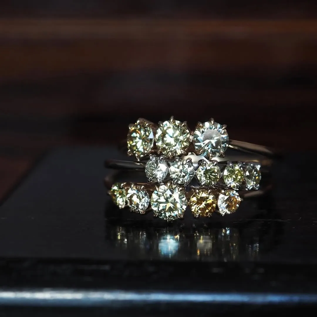 3つのダイヤモンドリングが黒い面に積み重ねられている写真