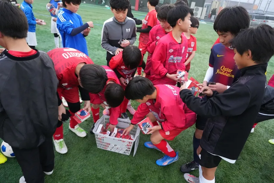 サッカーチームの少年たちが、何かを手に取っている様子