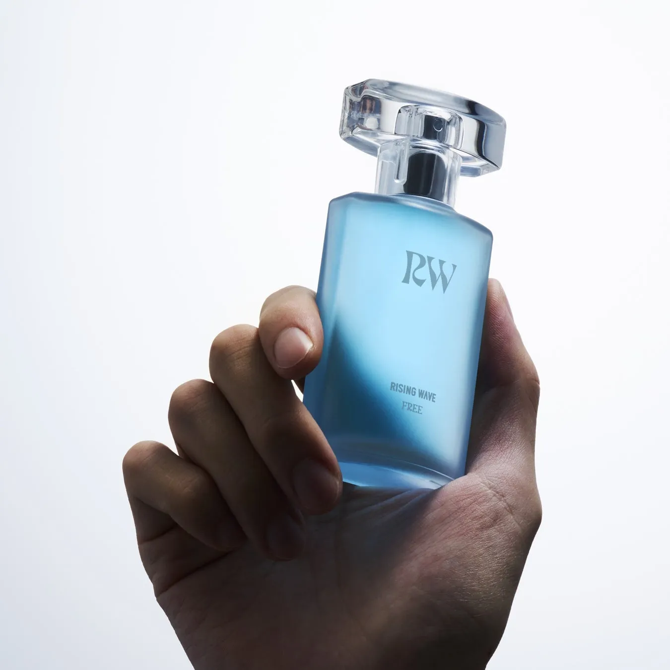 水色の香水瓶を手に持った手のクローズアップ