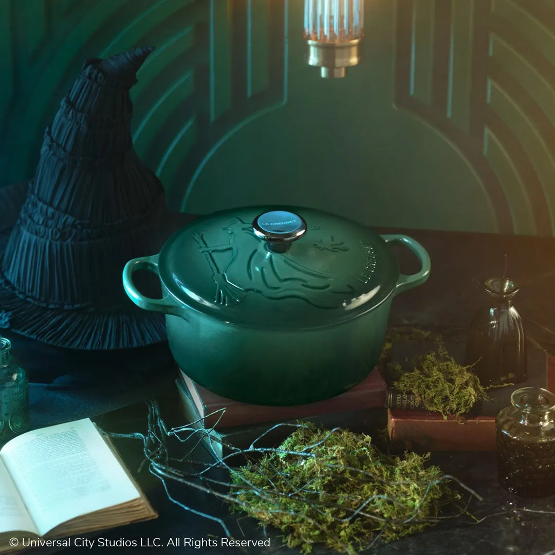 緑色の鍋と魔女の帽子、本、草、小瓶などが配置された、ハロウィーンをテーマにした写真です。