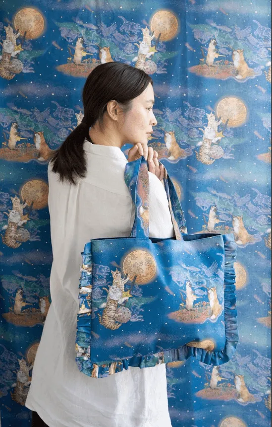 女性が猫の絵のトートバッグを持っている