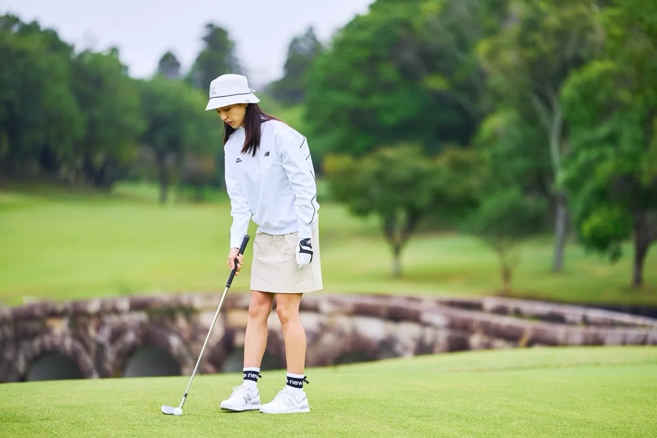 ゴルフ場でゴルフをする女性。ニューバランスのウェアを着て、帽子を被っている。