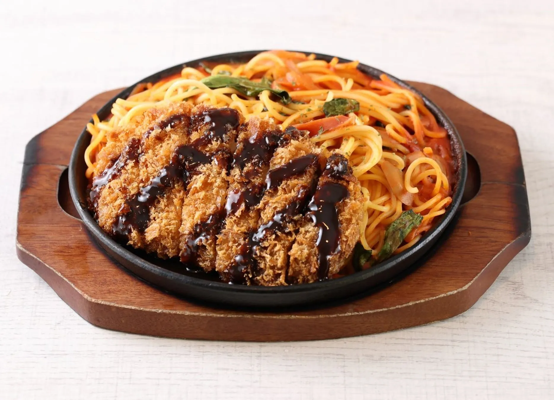 熱々の鉄板に盛られた揚げ物とパスタの料理