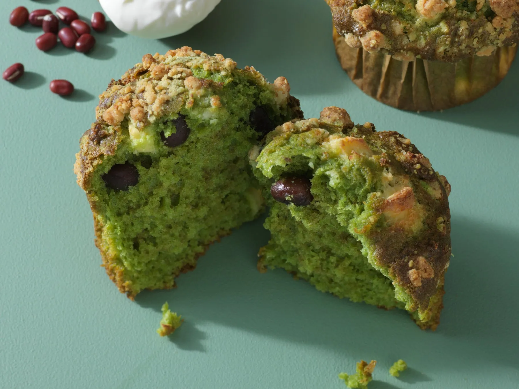 抹茶マフィンが半分にカットされ、中に小豆が入っている様子。周りには小豆とクリームが添えられている。