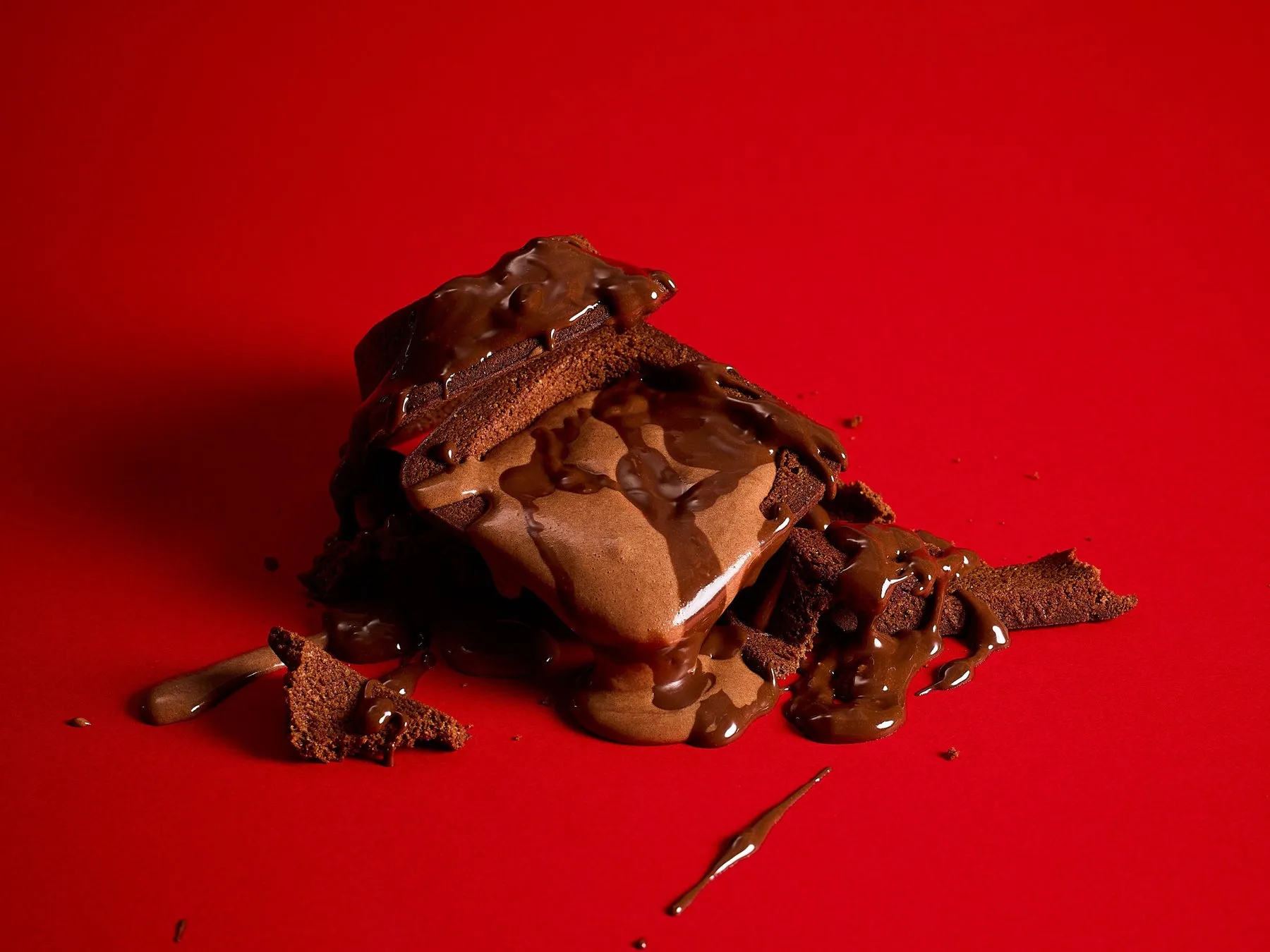 赤い背景に、チョコレートソースのかかったチョコレートケーキ