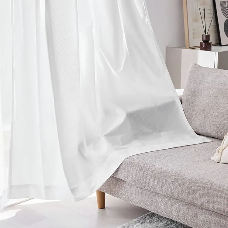 白いカーテンとグレーのソファのある部屋の様子