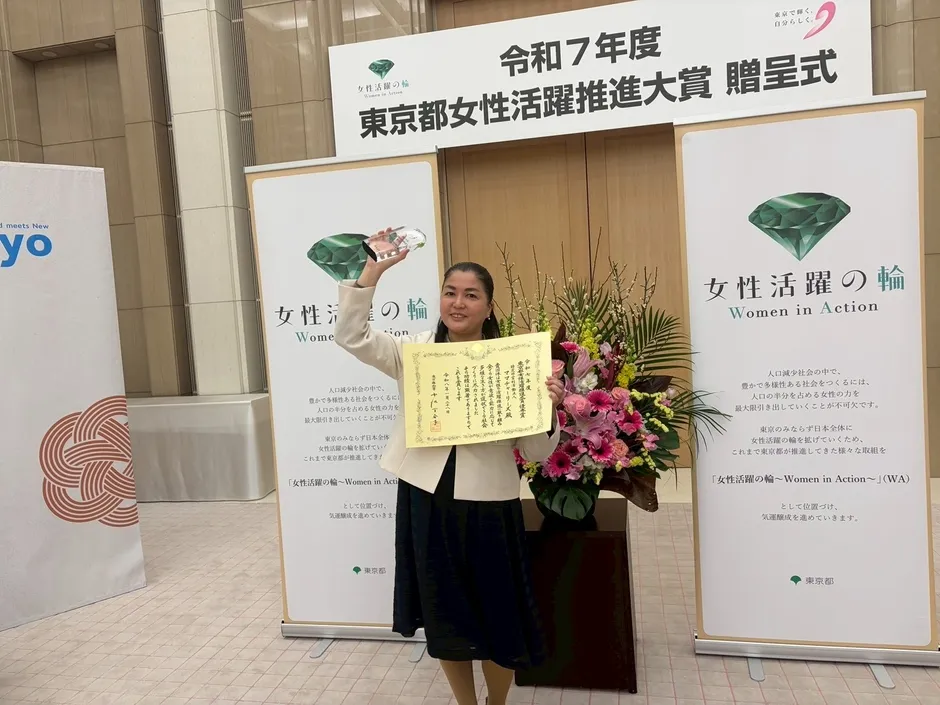 賞状とトロフィーを持って笑顔の成川理事長