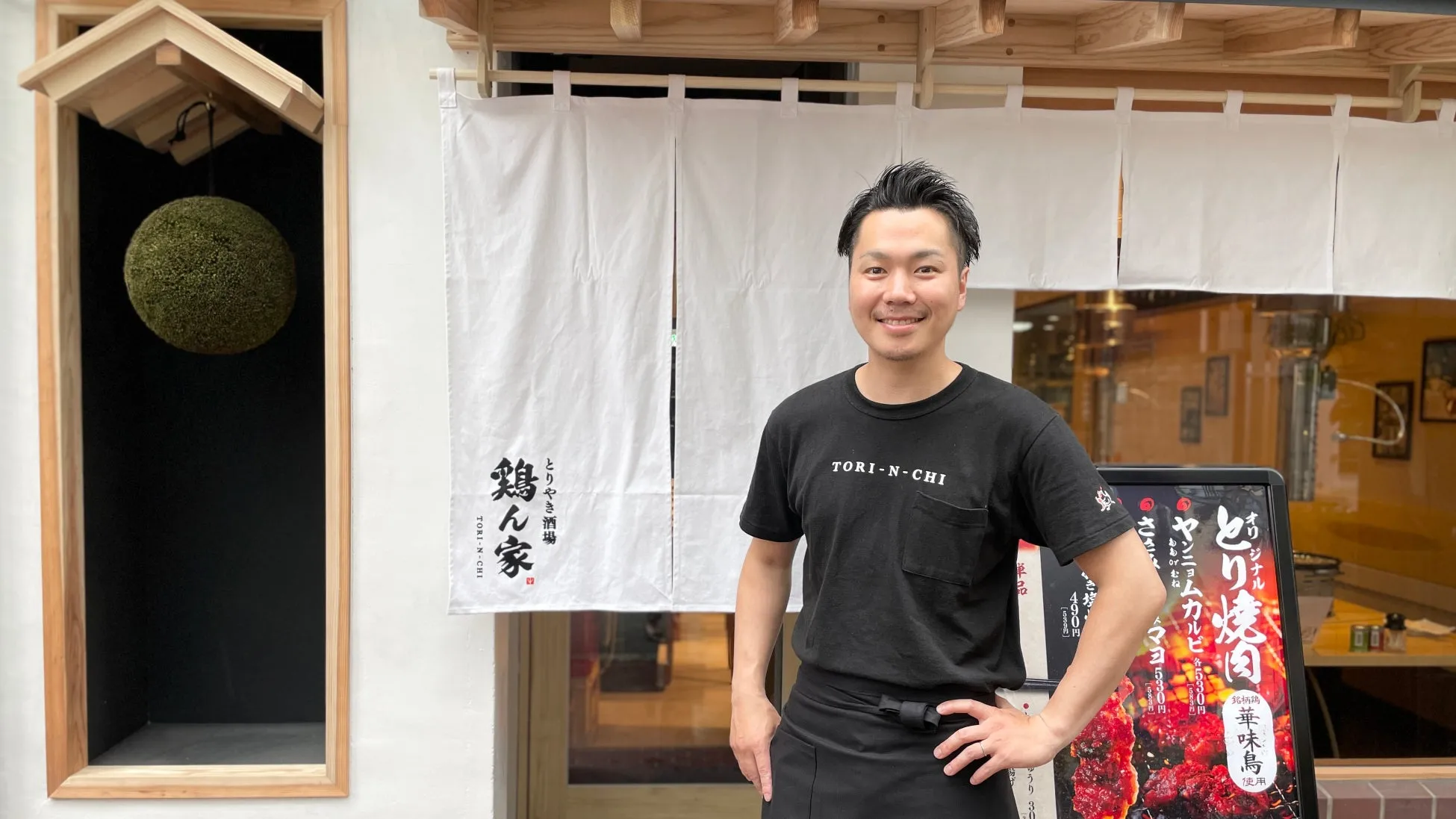 店の前で笑顔で立っている男性