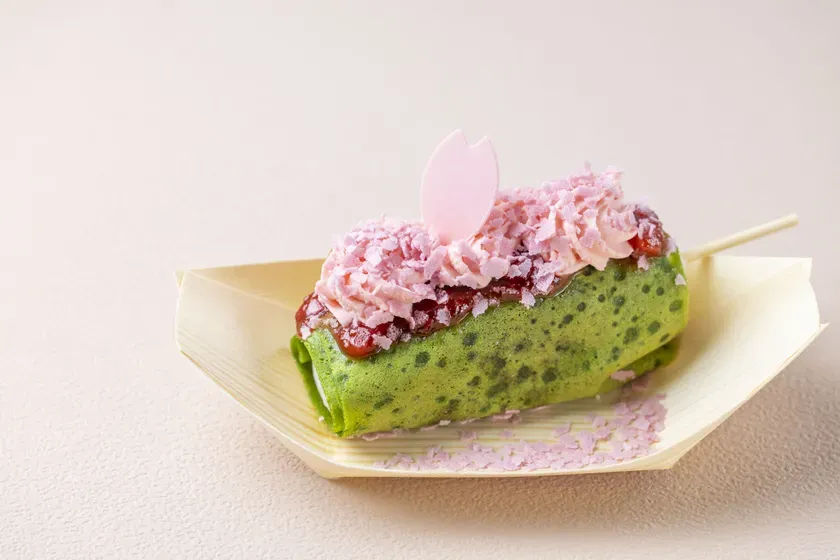 ピンク色のクリームと桜の形をした飾りでトッピングされたケーキ