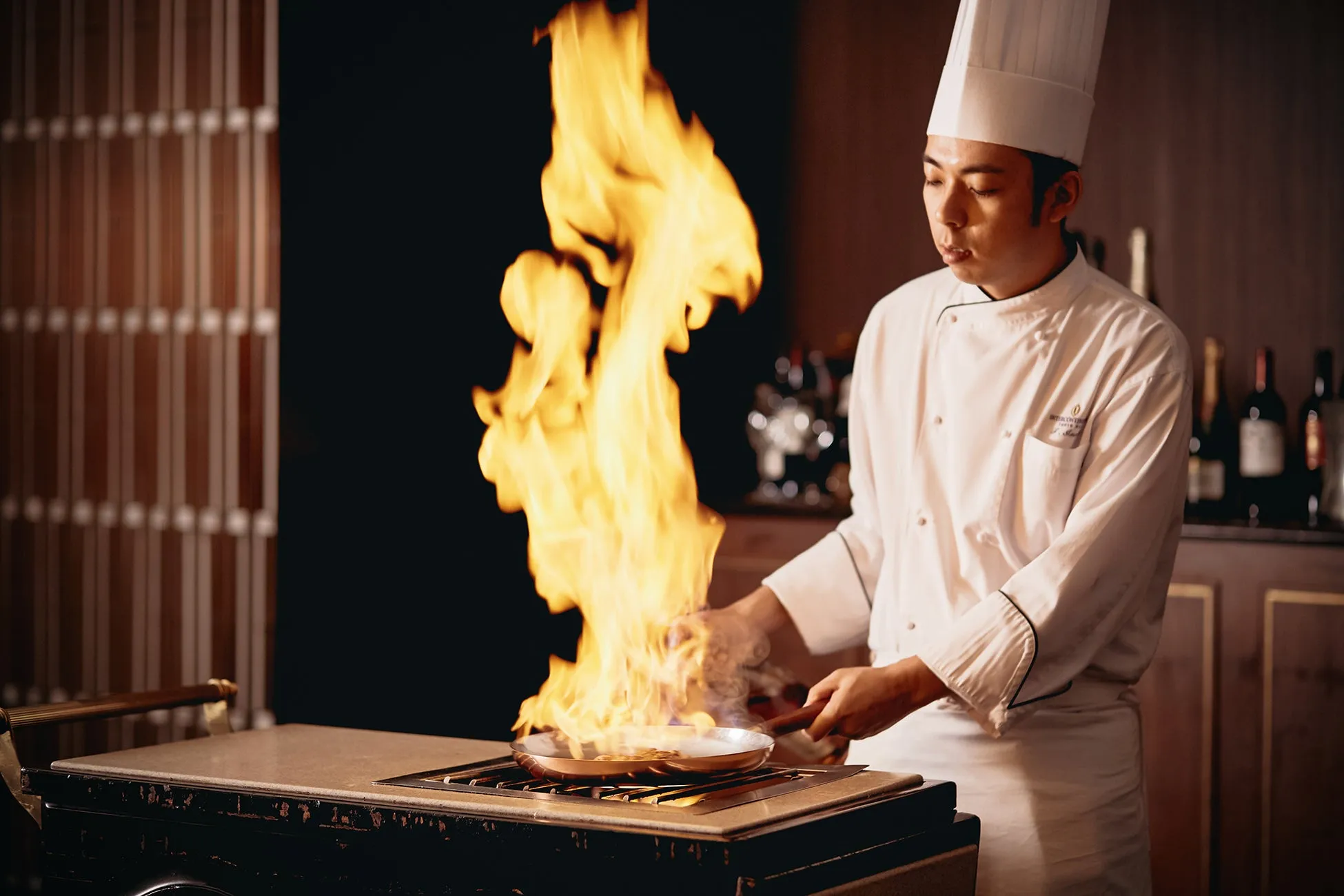 料理人が調理している様子。炎が上がり、鍋の中で料理が調理されている。