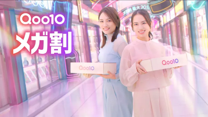 2人の女性がQoo10の箱を持ち、笑顔で立っている画像。背景にはネオンサインが光る通路が写っている。