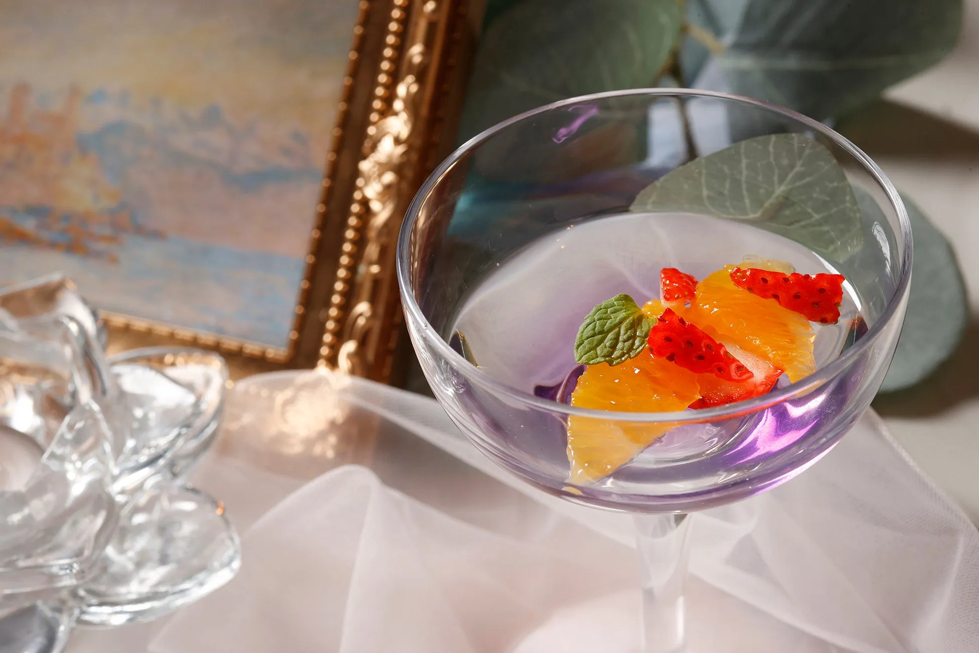 透明なグラスに入った、オレンジとイチゴ、ミントを添えたデザート。