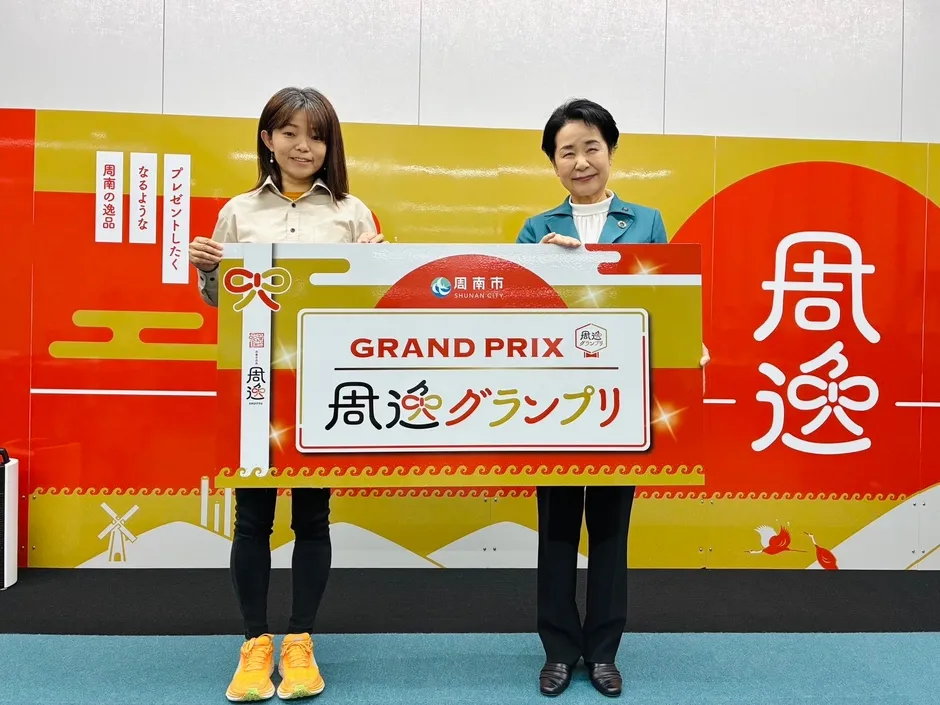 周逸グランプリの看板を持つ女性たち